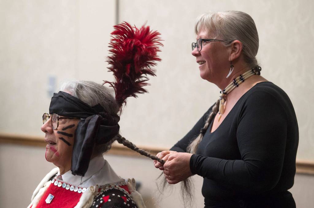 Michelle Rochette braids Walter Soboleff Jr.s hair before their group, the Yees Ku Oo Dancers, perform during Indigenous Peoples Day celebrations at the Elizabeth Peratrovich Hall on Monday, Oct. 8, 2018. (Michael Penn | Juneau Empire)