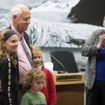 Outgoing Mayor Ken Koelsch, surrounded by his grandchildren, is acknowledged for his service by incoming Mayor Beth Weldon in a crowded Assembly chambers on Monday, Oct. 15, 2018. (Michael Penn | Juneau Empire)