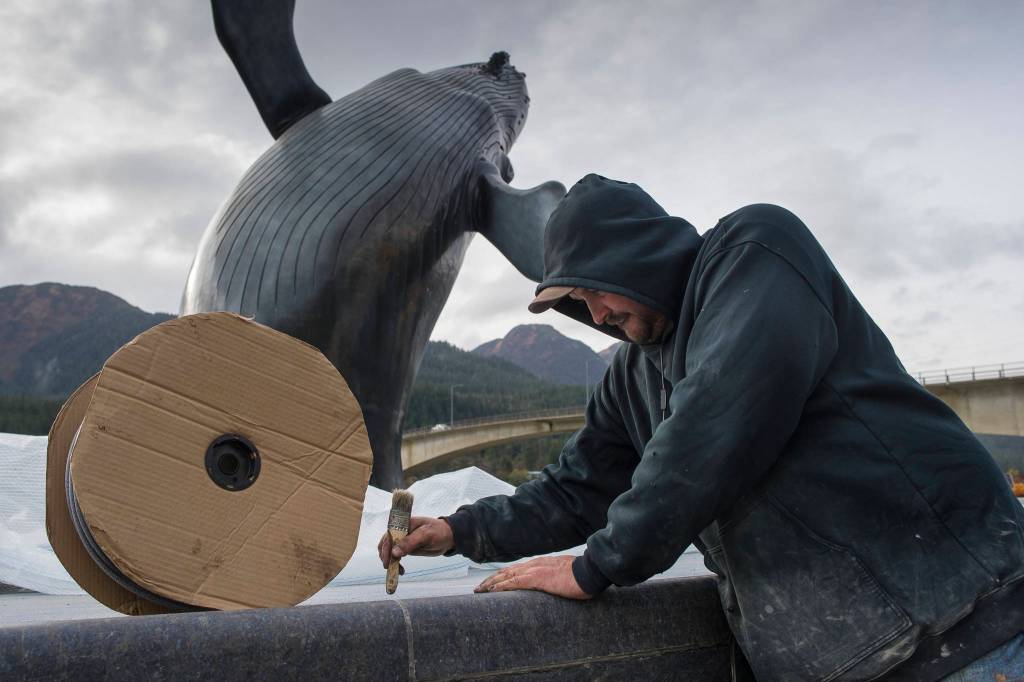 Ryan Hanson, of Admiralty Construction, does touch up work around the whale statue at the Mayor Bill Overstreet Park on Thursday, Oct. 18, 2018. The fountain is being shut down for winter. Hanson did not know if the statue lights will run through the winter. (Michael Penn | Juneau Empire)