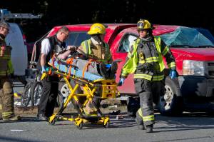 Capital City Fire/Rescue personnel wheel a man to a waiting ambulance at the scene of a two-car accident near the Egan Drive and Mendenhall Loop Road intersection in the Mendenhall Valley in March 2016. Two people were treated at Bartlett Regional Hospital for minor injuries. (Michael Penn | Juneau Empire File)