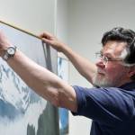 Dan Fruits hangs his paintings at the Juneau-Douglas City Museum as he readies for a summer-long exhibit. Fruits latest project has been paintings to be projected during the opera commissioned by the Orpheus Project will mark the 100th anniversary of the sinking of the Princess Sophia, which claimed the lives of more than 350 people. (Michael Penn | Juneau Empire)