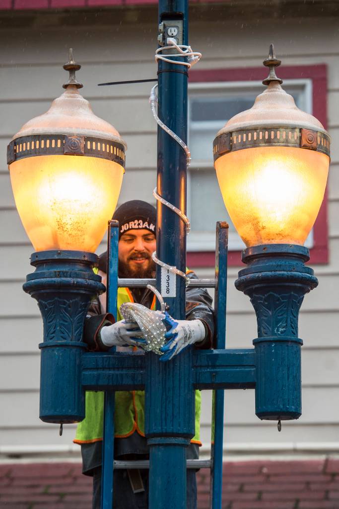 Charles Schneider, of the citys park maintenance division, decorates a lamp pole with holiday lighting along Franklin Street on Tuesday, Oct. 23, 2018. (Michael Penn | Juneau Empire)