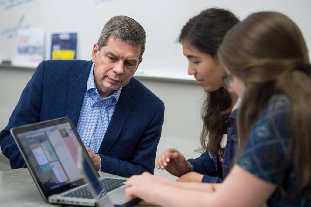 Democrat gubernatorial candidate Mark Begich watches as Thunder Mountain High School senior students Tristan Weissmuller, center, and Briannah Letter work on a candidate voter page during their government class on Friday, Oct. 26, 2018. (Michael Penn | Juneau Empire)