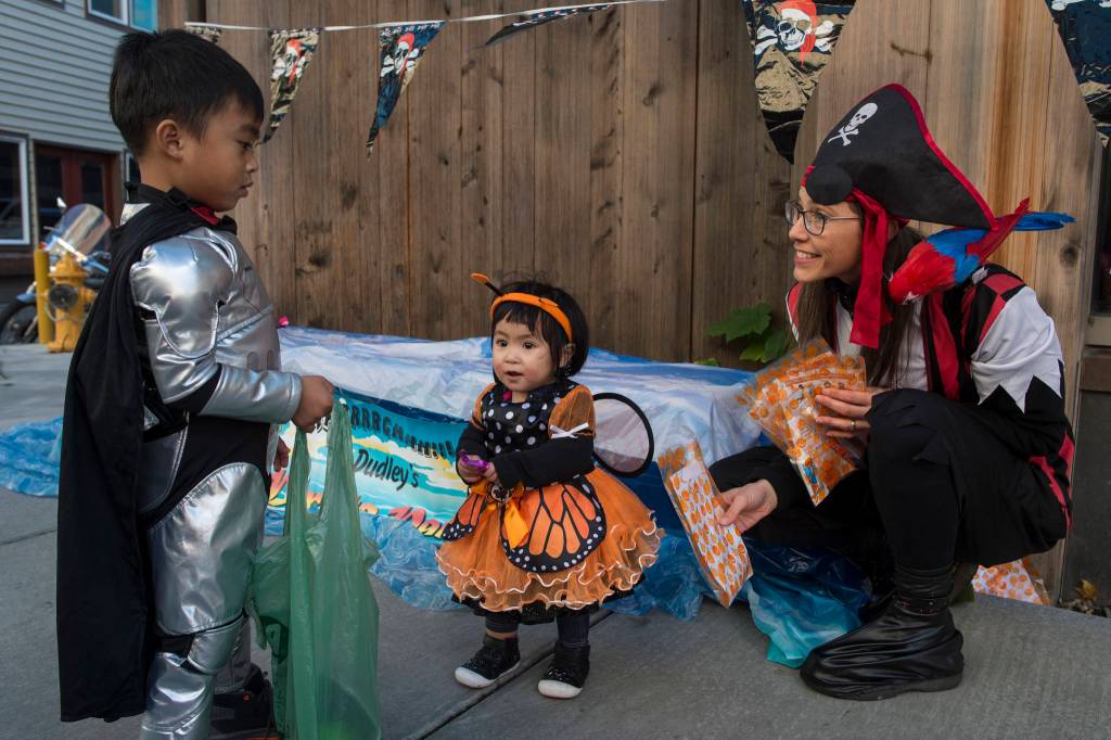 Dr. Kim Hort, Pediatric Dentist Manager for the SouthEast Alaska Regional Health Consortiums Childrens Dental Clinic, hands out candy and toothbrushes to Jared Lumba, 4, and his sister, Sue, 1, on Front Street on Wednesday, Oct. 31, 2018. For the fourth year Kindred Post has organized the Halloween celebration for trick-or-treaters. (Michael Penn | Juneau Empire)