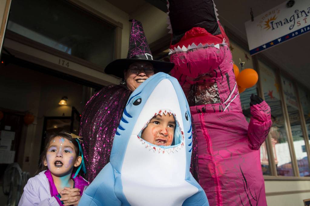 Laura Cooper and her twins, Tanner and Amara, 5, visit with T-Rex, Timieka Sullen, in front of the Imagination Station on Wednesday, Oct. 31, 2018. For the fourth year Kindred Post has organized the Halloween celebration for trick-or-treaters. (Michael Penn | Juneau Empire)