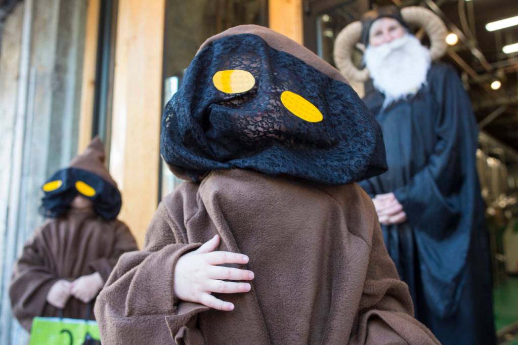 Aurelia Peoples, 4, center, and Mia Belvins, 3, are costumed as Jawas as they visit DJ Thomson at Devils Club Brewery on Wednesday, Oct. 31, 2018. For the fourth year Kindred Post has organized the Halloween celebration for trick-or-treaters. (Michael Penn | Juneau Empire)