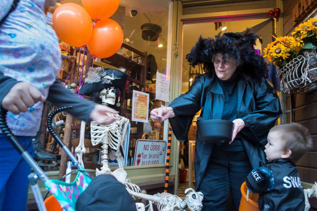 Suzanne Hudson, owner of Nanas Attic, hands out candy to visiting children and their parents on Wednesday, Oct. 31, 2018. For the fourth year Kindred Post has organized the Halloween celebration for trick-or-treaters. (Michael Penn | Juneau Empire)