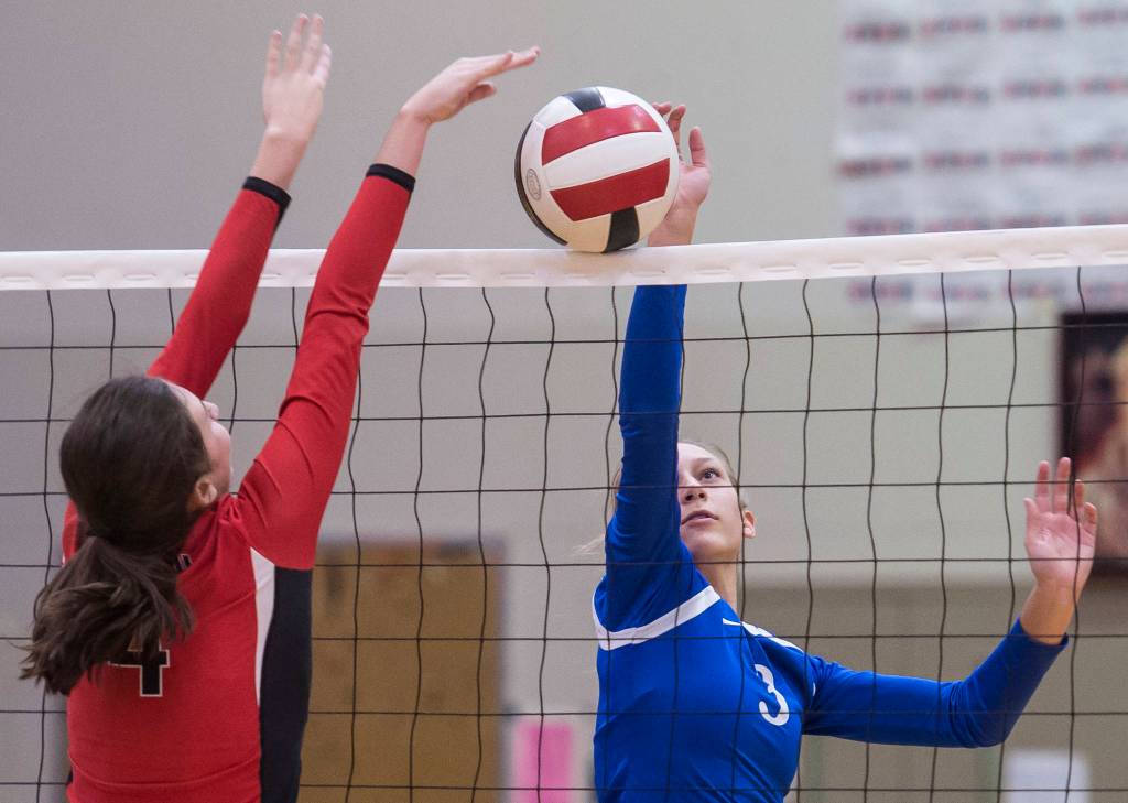 Thunder Mountains Lily Smith, right, tips the ball over against Juneau-Douglas Jenae Pusich during the second round of the Region V Volleyball Championships at JDHS on Friday, Nov. 2, 2018. TMHS won 3-1 (25-20, 25-10, 16-25, 25-21). (Michael Penn | Juneau Empire)