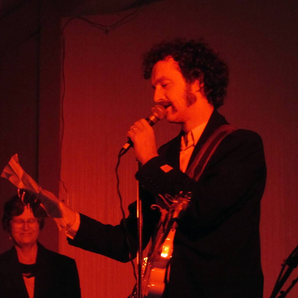 George C. Kuhar takes a break from propulsive guitar boogie to read from a letter written to his late father during the annual Skull Party held Friday evening at the Rockwell Ballroom. Ben Hohenstatt | Capital City Weekly)