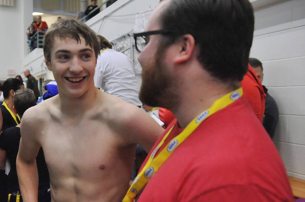 Juneau-Douglas High School senior Tyler Weldon speaks with coach Seth Cayce following his third-place finish in the 50-yard freestyle on Saturday at the ASAA/First National Bank Alaska Swim & Dive Championships at Bartlett Pool in Anchorage. The second through eighth-place finishers all finished within 0.51 seconds of one another. (Michael Dinneen | For the Juneau Empire)