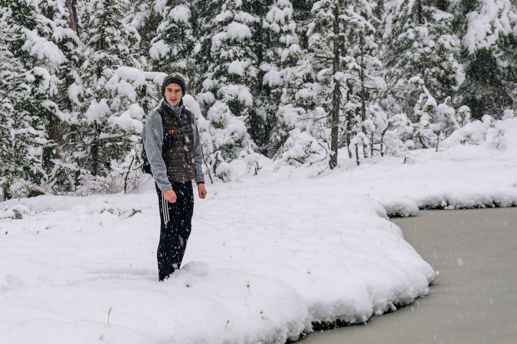 Ian McGonegal approaches edge of pond while snow continues to fall. (Gabe Donohoe | For the Juneau Empire)