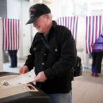 Dr. Johnny Holland feeds his ballot into a counting machine while voting during a special election for mayor of Juneau at the Mendenhall Valley Public Library in 2016. The Alaska Division of Elections is considering new voting equipment statewide. (Michael Penn | Juneau Empire file)