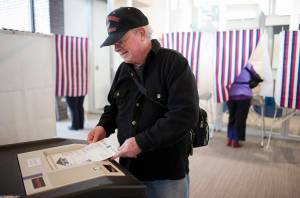 Dr. Johnny Holland feeds his ballot into a counting machine while voting during a special election for mayor of Juneau at the Mendenhall Valley Public Library in 2016. The Alaska Division of Elections is considering new voting equipment statewide. (Michael Penn | Juneau Empire file)