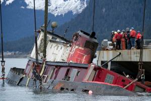 Crew aboard the barge-crane Brightwater lifts the sunken 96-foot tugboat Challenger in Gastineau Channel in February 2016. The federal government has filed a civil lawsuit against Juneau artist R.D. Robinson, alleging he is responsible for the cost of removing the ship from Gastineau Channel. (Michael Penn | Juneau Empire file)