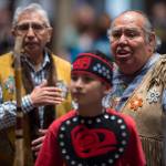 Tlingit elders David Katzeek, right, and Paul Marks, left, watch as Tyler Frisby, a member of the Tlingit Culture Language and Literacy Dance Group from Harborview Elementary School dance exits during the Voices of Our Ancestors Language Summit at Centennial Hall on Tuesday, Nov. 13, 2018. (Michael Penn | Juneau Empire)