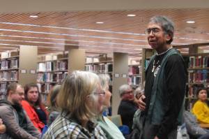 Bob Sam, a Tlingit storyteller who has served as caretaker of a Sitka cemetery for decades and works to repatriate and reinter indigenous people, leaves the lectern to walk into the crowd during his Evening at Egan lecture about respecting ancestors Friday, Nov. 16 at Egan Library. (Ben Hohenstatt | Capital City Weekly)