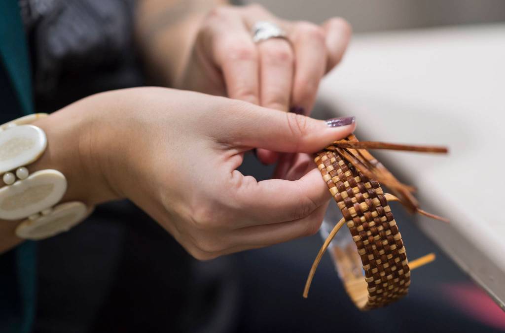 Heather Gatti works on a cedar root braclett at the Celebrating Our Ways of Life for Native American Heritage Month at the Elizabeth Peratrovich Hall on Friday, Nov. 16, 2018. (Michael Penn | Juneau Empire)