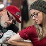 Tattoo artist Mario Singh applies a stylized semicolon to the back of Amy Ridles upper arm at Taku Tattoo on Monday, Nov. 19, 2018. (Michael Penn | Juneau Empire)