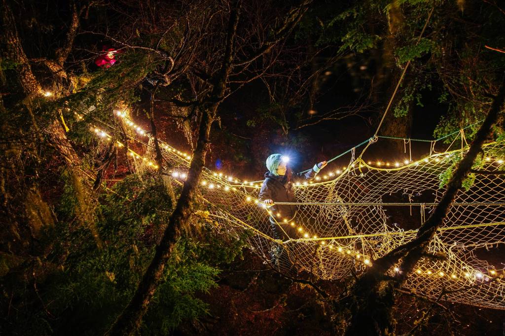 Claire crosses net bridge from land to tree. (Gabe Donohoe | For the Juneau Empire)