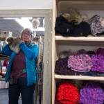 Carol Bruce tries on a hat at the W.W. Knits booth at the Public Market in Centennial Hall on Friday, Nov. 23, 2018. (Michael Penn | Juneau Empire)
