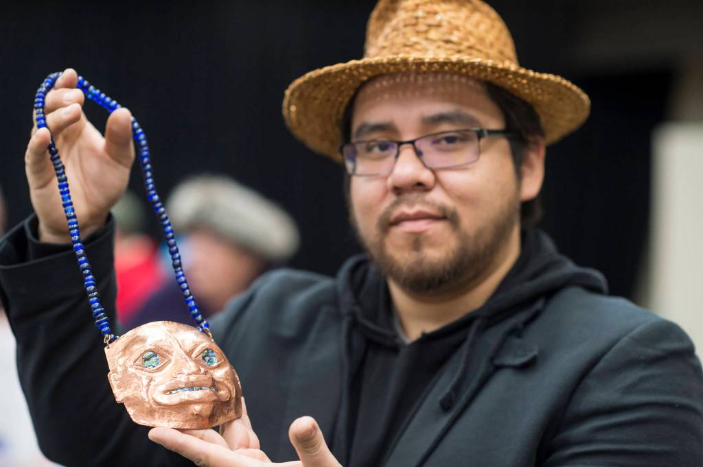 Samuel Sheakley Sr. shows of his copper piece titled Koo.eex Spirit at the Public Market in the Elizabeth Peratrovich Hall on Friday, Nov. 23, 2018. (Michael Penn | Juneau Empire)
