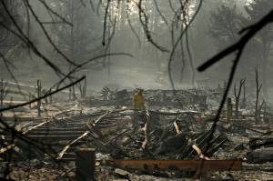 In this Nov. 16, 2018 photo, a firefighter searches for human remains in a trailer park destroyed in the Camp Fire, in Paradise, California. The massive wildfire that killed dozens of people and destroyed thousands of homes has been fully contained after burning for more than two weeks, authorities said Sunday, Nov. 25. (John Locher | Associated Press File)