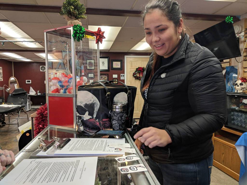 Davina Cole shows sketches of a tattoo she planned to get during a suicide prevention event at Taku Tattoo Friday, Nov. 30. Coles design included influence of the Northwest art form formline. (Ben Hohenstatt | Capital City Weekly)
