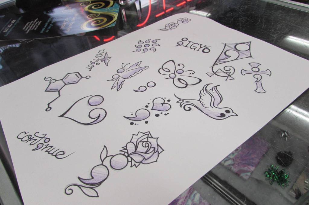 While many customers came in with their own designs for a suicide prevention special event at Taku Tattoo, Friday, Nov. 30, 2018, Salty Jack Reed Jr. came prepared with some designs. (Ben Hohenstatt | Capital City Weekly)