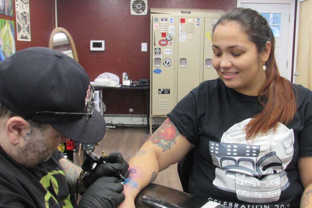 Salty Jack Reed Jr. puts the finishing touches on Davina Coles formline semicolon tattoo Friday, Nov. 30, 2018. (Ben Hohenstatt | Capital City Weekly)