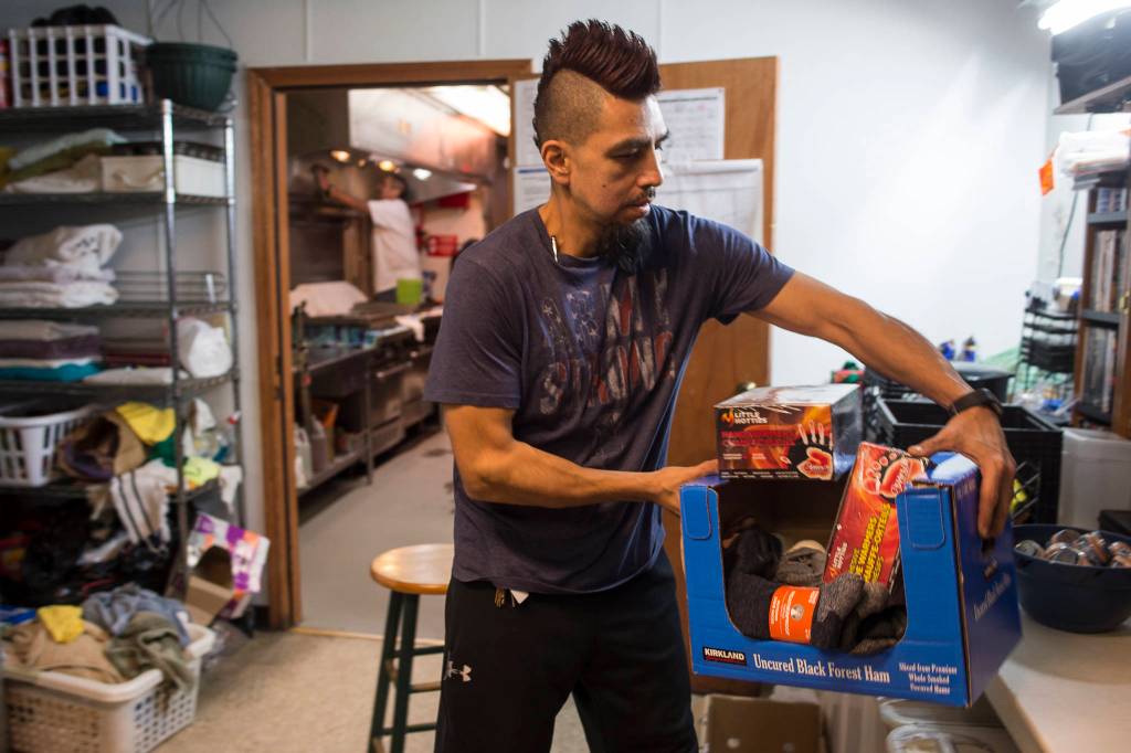 Marti Fred, facility coordinator for the Glory Hall, puts away donations of wool socks and hand warmers at the local soup kitchens and homeless shelter on Friday, Dec. 7, 2018. (Michael Penn | Juneau Empire)