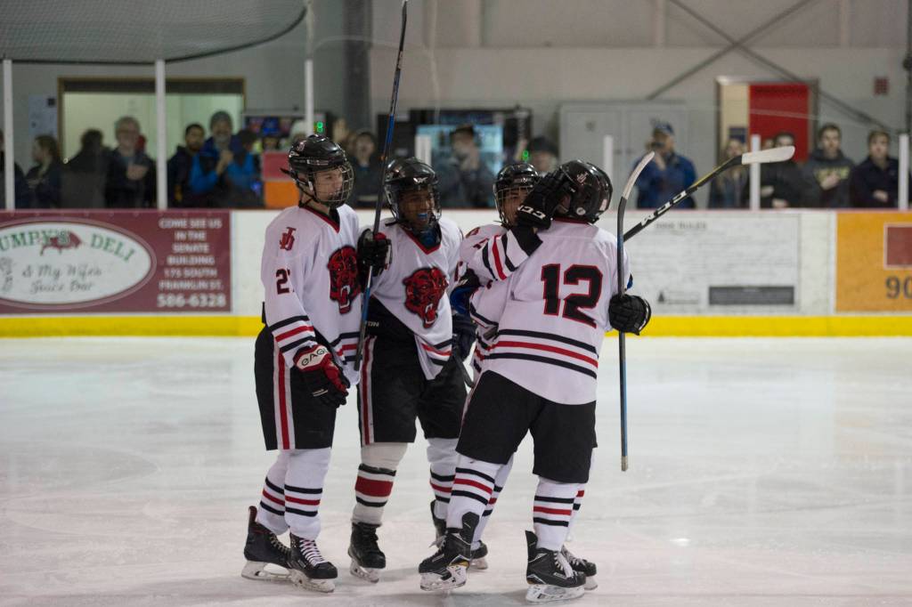 Juneau-Douglas Josh Frisby congratulates Kyler Alderfer on his third-period goal that made it 6-0 while Tyler Weldon, far left, and Finn Yerkes, look on. JDHS defeated Houston 7-0. (Nolin Ainsworth | Juneau Empire)