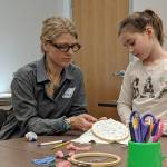 Artist Amy Meissner works with Ellinore Higgins, 7, during an embroidery activity for kids Saturday, Dec.8, 2018 at the Alaska State Library, Archives and Museum. (Ben Hohenstatt | Capital City Weekly)