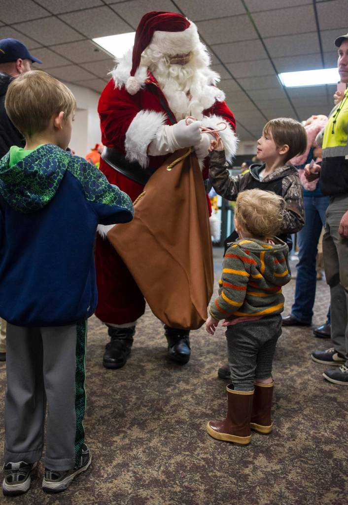 Santa gives out candy canes to children waiting in line for the annual Christmas Lights Flights at the Juneau International Airport on Friday, Dec. 15, 2017. Mendenhall Flying Lions put on the event, which is a fundraiser for the American Childrens Tumor Foundation. Petro Marine Services and Coastal Fuel also support the event. (Michael Penn | Juneau Empire File)