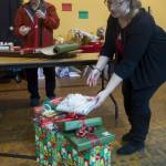 Jenny Rodriguez, right, and Gene Laughlin make use of the Christmas wrapping station at the Juneau Arts and Culture Center to finish off their gifts. For a donation people can find wrapping paper and all the trimmings. The JACC will be open every day and until 3 p.m. on Sunday, Christmas Eve. (Michael Penn | Juneau Empire File)