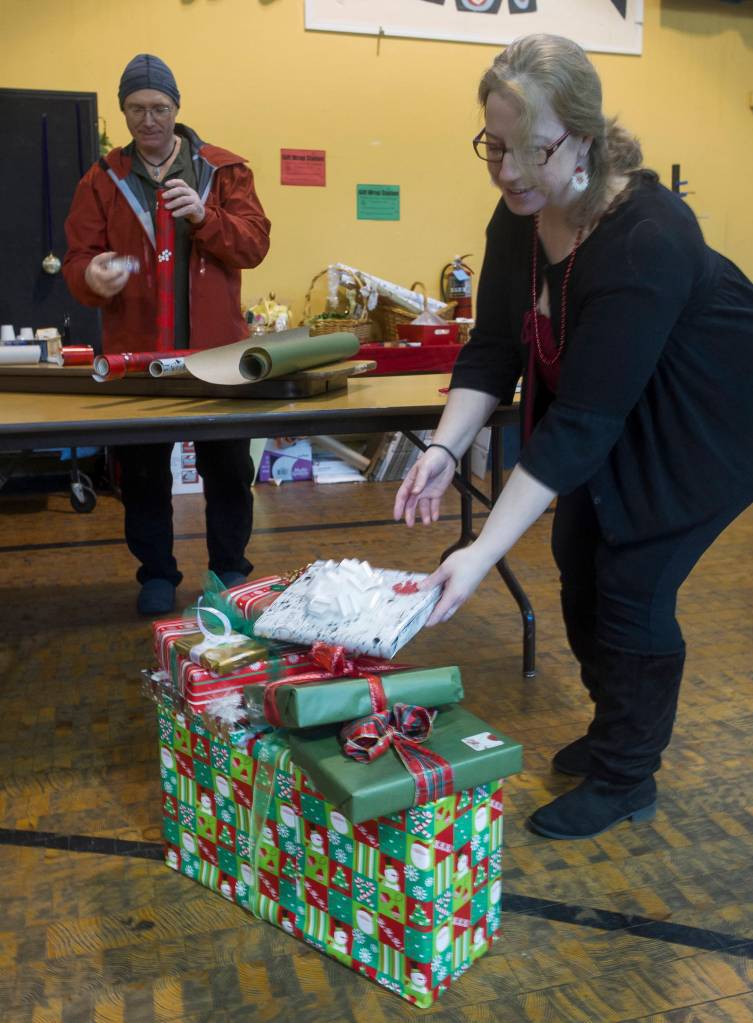 Jenny Rodriguez, right, and Gene Laughlin make use of the Christmas wrapping station at the Juneau Arts and Culture Center to finish off their gifts. For a donation people can find wrapping paper and all the trimmings. The JACC will be open every day and until 3 p.m. on Sunday, Christmas Eve. (Michael Penn | Juneau Empire File)