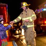 In this file photo, Capital City Fire/Rescue firefighter David Edmunds hands out candle canes to Joanna Magalotti, 6, and her sister, Joella, 3, as firemen make their way through town in December 2012 as part of their annual Santa on a Fire Truck event in Juneau and Douglas. (Michael Penn | Juneau Empire)
