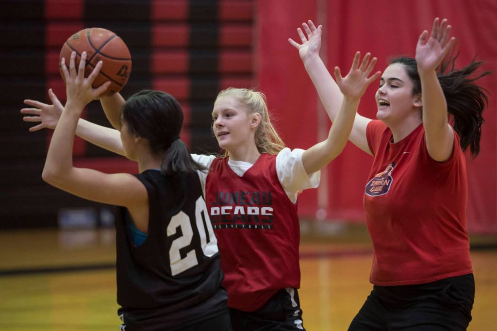 Sadie Tuckwood, center and Chloe McAdams, right, apply pressure to Bailey Wery-Tagaban during Juneau-Douglas High School girls varsity practice on Thursday, Dec. 6, 2018. (Michael Penn | Juneau Empire)