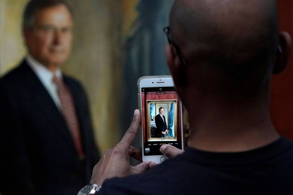 Ayman Tahir takes a photo of a painting of George H.W. Bush inside the George H.W. Bush Library and Museum Saturday, Dec. 1, 2018, in College Station. Bush has died at age 94. Family spokesman Jim McGrath says Bush died shortly after 10 p.m. Friday, Nov. 30, 2018, about eight months after the death of his wife, Barbara Bush. (David J. Phillip | Associated Press)