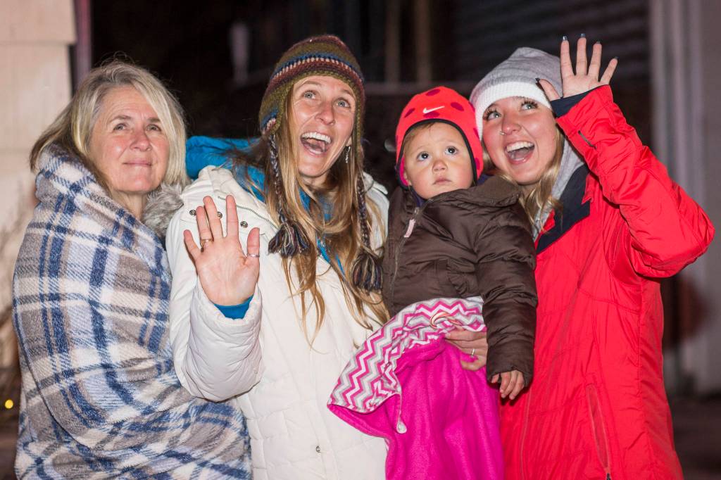 Bailey Thurman, left, Laura Lupercio, holding 3-year-old Lane, and Bailey Thurman wave to Mr. and Mrs. Santa in Douglas during the annual Capital City Fire/Rescue Santa Parade on Friday, Dec. 14, 2018. (Michael Penn | Juneau Empire)