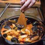 Erin Anais Heist prepares her tomato-based Portuguese fishermans stew with a variety of seafood, spicy sausage, potatoes and smoked paprika in her home kitchen on Friday, Dec. 14, 2018. (Michael Penn | Juneau Empire)