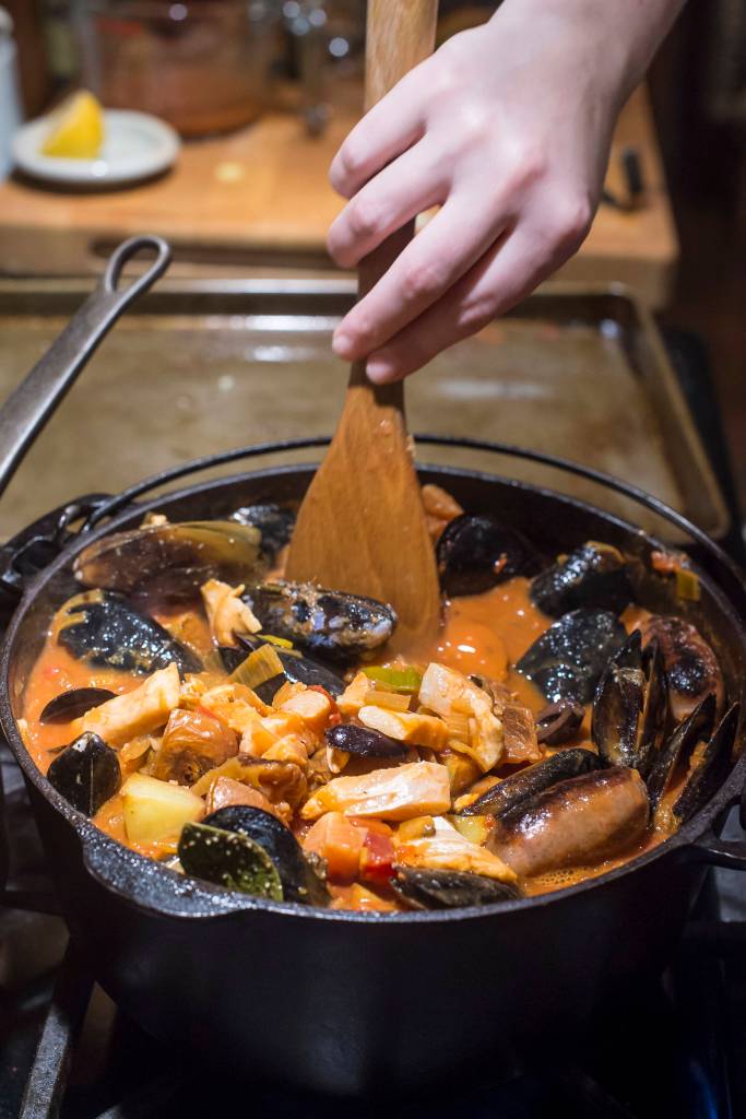 Erin Anais Heist prepares her tomato-based Portuguese fishermans stew with a variety of seafood, spicy sausage, potatoes and smoked paprika in her home kitchen on Friday, Dec. 14, 2018. (Michael Penn | Juneau Empire)