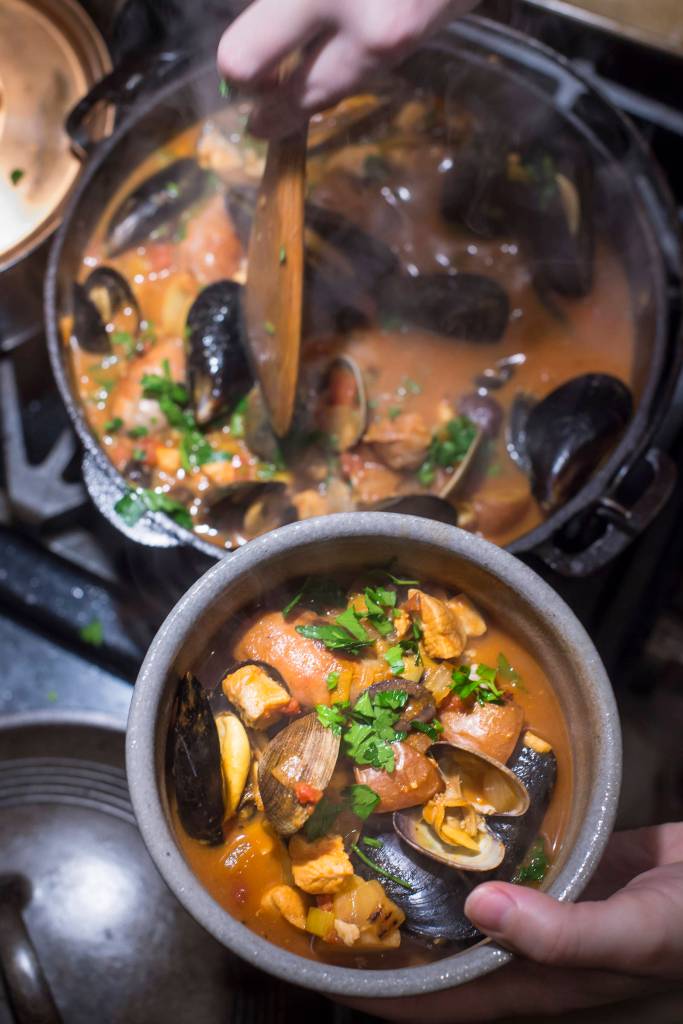 Erin Anais Heist prepares her tomato-based Portuguese fishermans stew with a variety of seafood, spicy sausage, potatoes and smoked paprika in her home kitchen on Friday, Dec. 14, 2018. (Michael Penn | Juneau Empire)