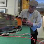Mike Orford adjusts one of his model trains while another zips along its tracks in the Juneau-Douglas City Museum, Saturday, Dec. 22,2018. (Ben Hohenstatt | Capital City Weekly)