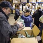 Super Bear/Foodland IGA employees Whitney Oudekerk, center, and Michael Stults, right, hand off bags of food for Superbear Director Tony Demelo to box at Superbear on Wednesday, Dec. 19, 20128, as part of the grocerys 3 Square program. (Michael Pernn | Juneau Empire)
