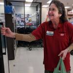 Mary Lou Stone, supervisor for Super Bear Supermarket IGA, puts a bag of groceries ready for pickup in a cooler near the front of the store on Thursday, Dec. 27, 2018. (Ben Hohenstatt | Juneau Empire)