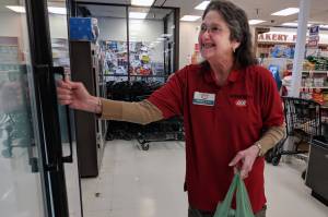 Mary Lou Stone, supervisor for Super Bear Supermarket IGA, puts a bag of groceries ready for pickup in a cooler near the front of the store on Thursday, Dec. 27, 2018. (Ben Hohenstatt | Juneau Empire)