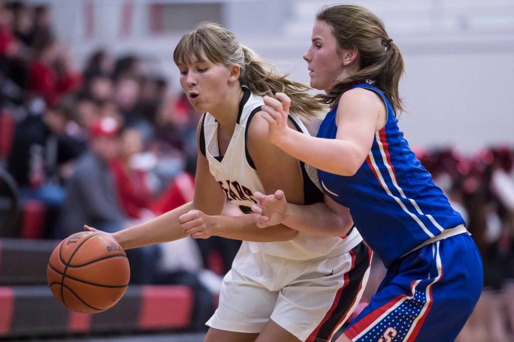 Juneau-Douglas Caitlin Pusich, left, drives against Sitkas Tawny Smith at the Princess Cruises Capital City Classic at Juneau-Douglas High School on Thursday, Dec. 27, 2018. Juneau-Douglas won 52-25. (Michael Penn | Juneau Empire)