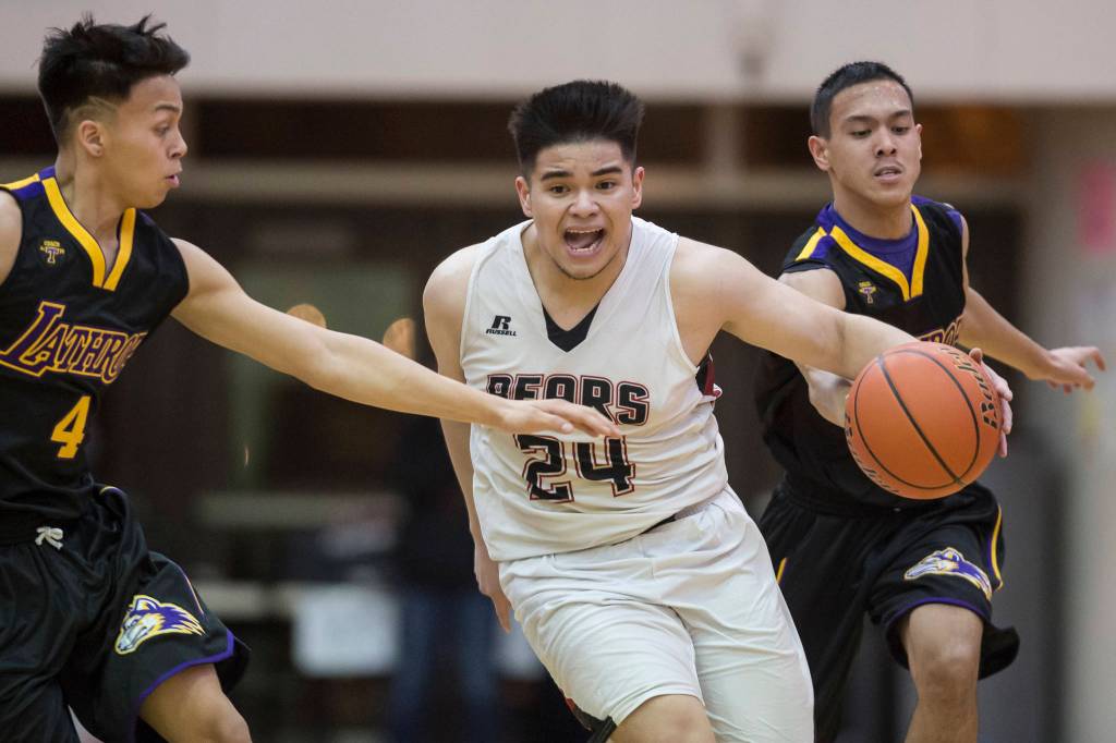 Juneau-Douglas Phillip Gonzales, center, drives between Lathrops Damian Correa, left, and Jhon Rones at the Princess Cruises Capital City Classic at Juneau-Douglas High School on Thursday, Dec. 27, 2018. Juneau-Douglas won 69-45. (Michael Penn | Juneau Empire)