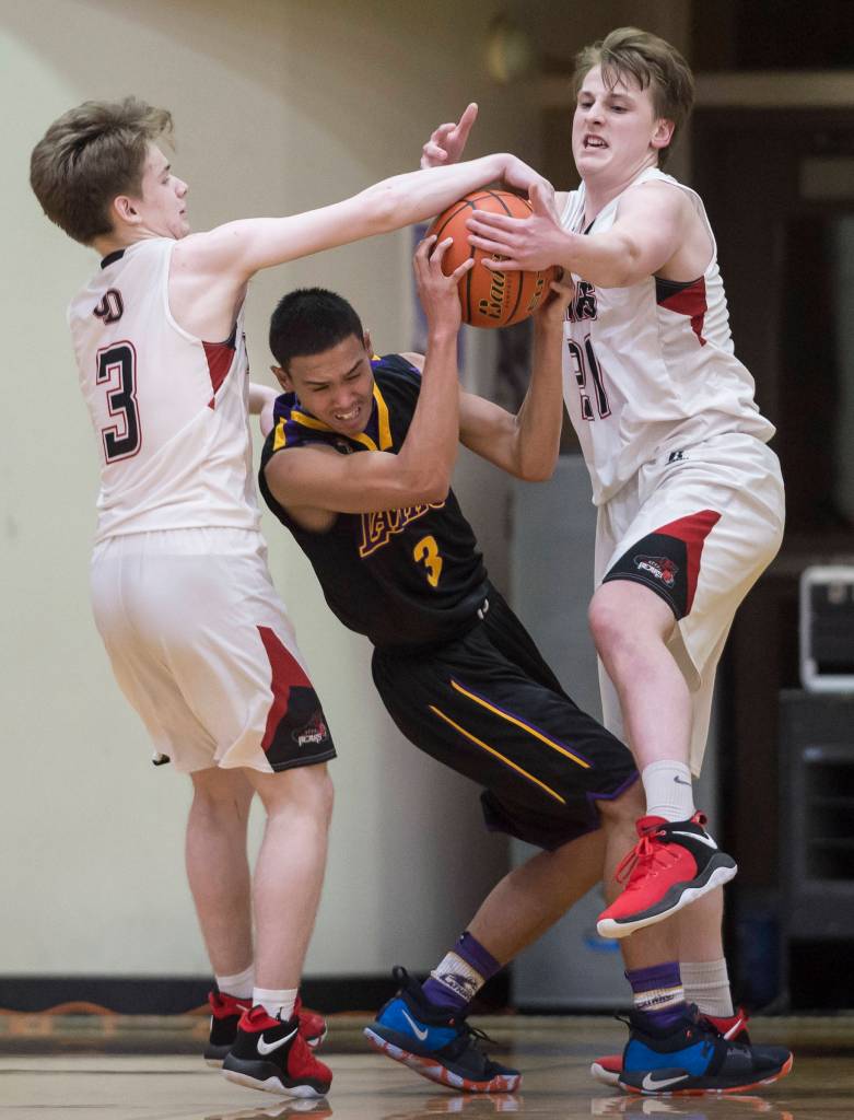 Juneau-Douglas Austin McCurley, left, and Tad Watson, right, pressure Lathrops Jhon Rones at the Princess Cruises Capital City Classic at Juneau-Douglas High School on Thursday, Dec. 27, 2018. Juneau-Douglas won 69-45. (Michael Penn | Juneau Empire)