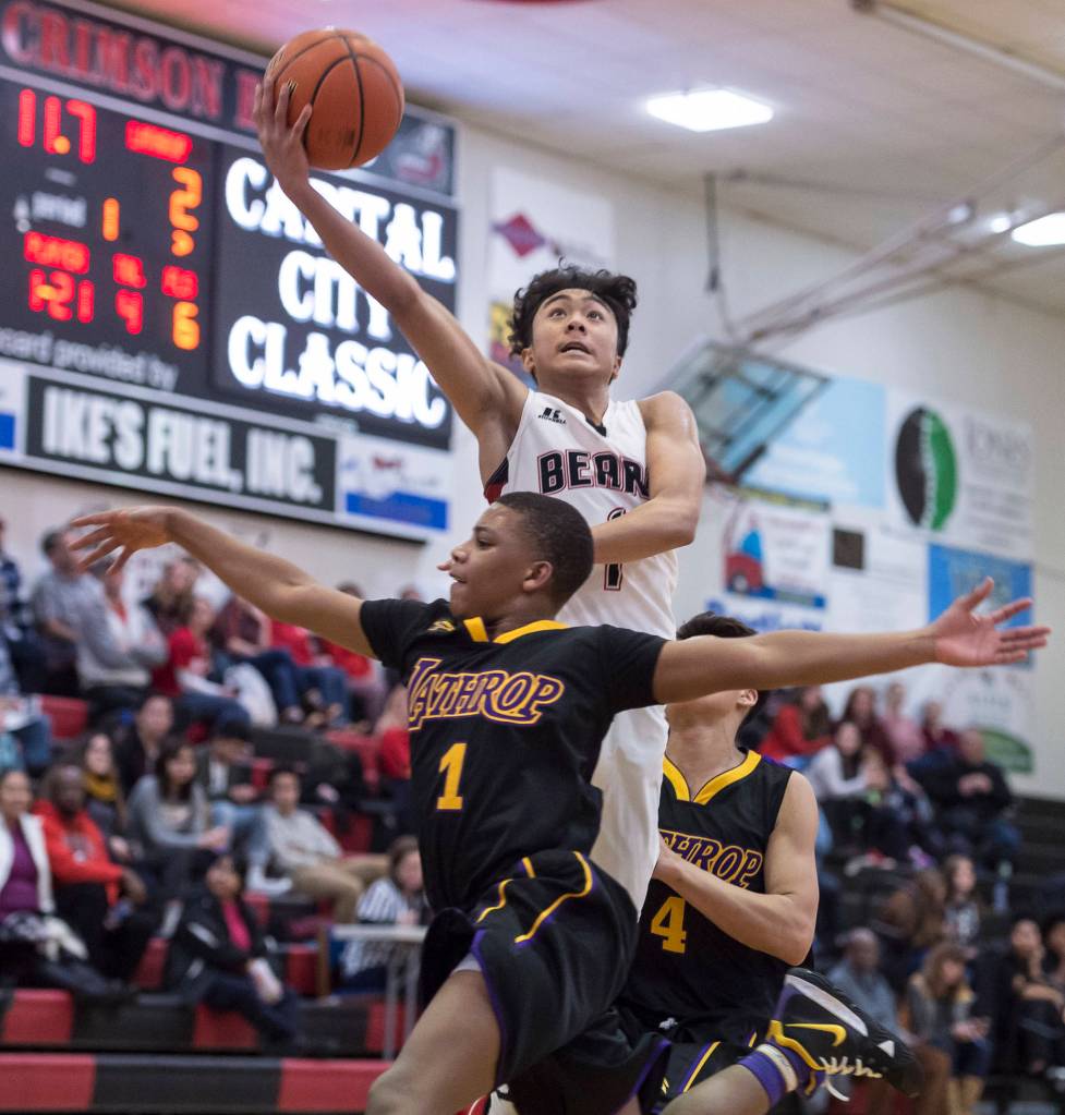 Juneau-Douglas Israel Yadao lays the ball up over Lathrops Jakobee Johnson at the Princess Cruises Capital City Classic at Juneau-Douglas High School on Thursday, Dec. 27, 2018. Juneau-Douglas won 69-45. (Michael Penn | Juneau Empire)